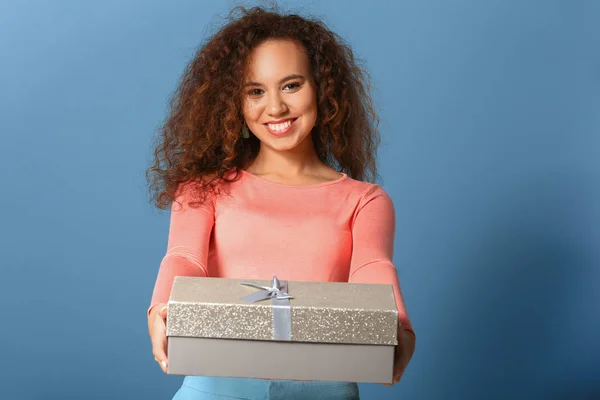 Beautiful young woman with gift on color background — Stock Photo, Image