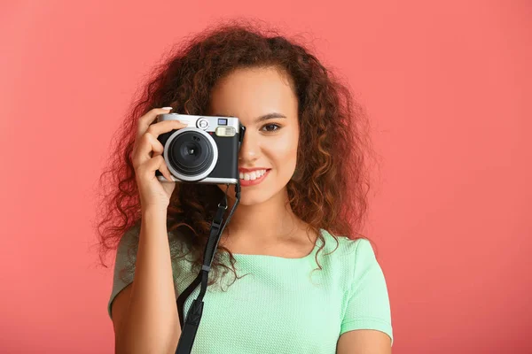 Mooie jonge vrouw met fotocamera op kleur achtergrond — Stockfoto