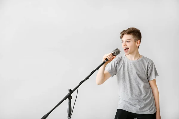 光の背景に対して歌うマイクを持つ十代の少年 — ストック写真