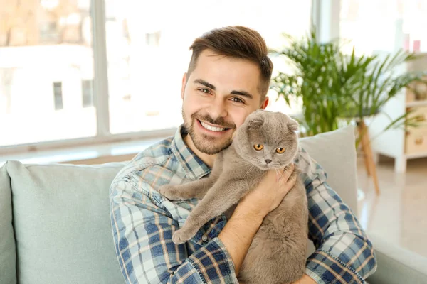 Young man with cute funny cat at home — Stock Photo, Image