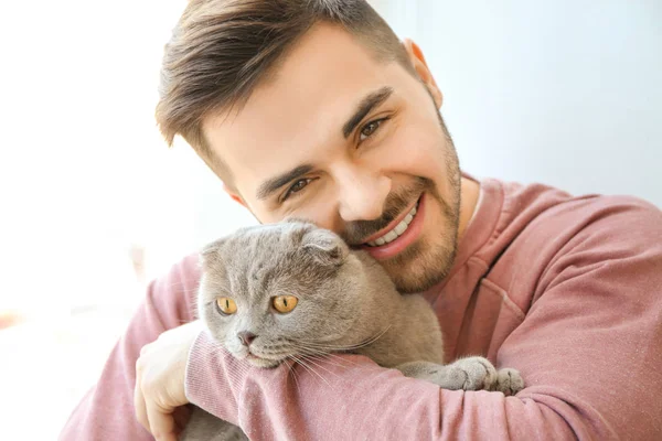 Young man with cute funny cat near window — Stock Photo, Image