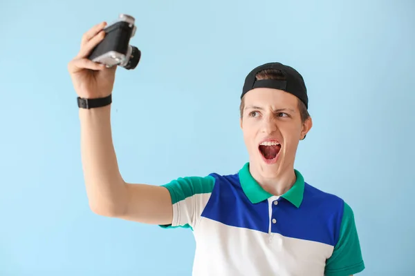 Nastoletni chłopiec z aparatem fotograficznym robienia selfie na kolorowym tle — Zdjęcie stockowe