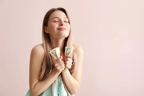 Happy young woman with money on color background — Stock Photo, Image