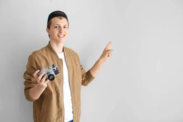 Nastoletni chłopiec z aparatem fotograficznym wskazując na coś na jasnym tle — Zdjęcie stockowe