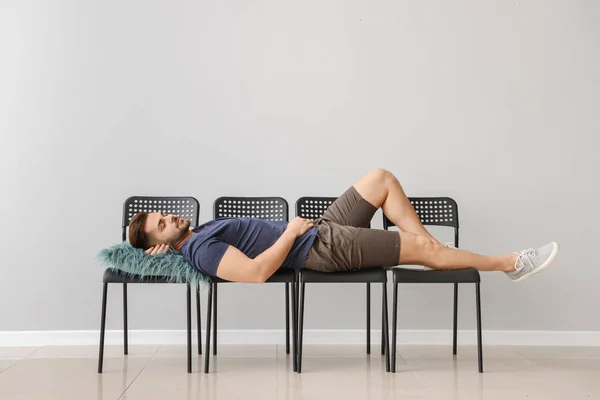 회색 벽 근처 의자에 자고 있는 잘생긴 남자 — 스톡 사진