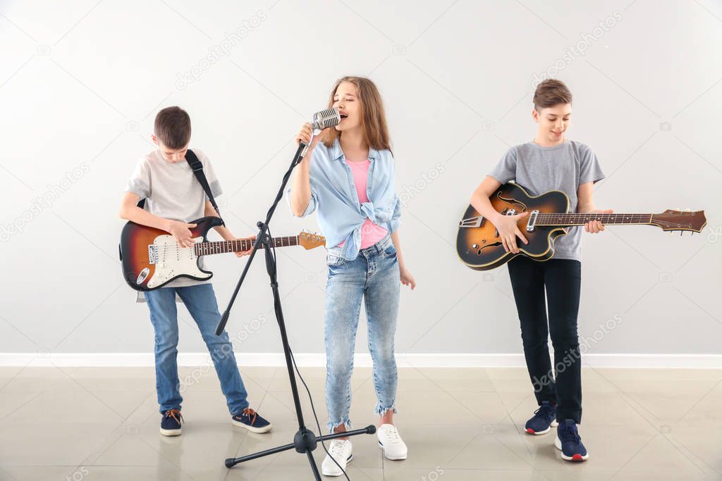 Teenage musicians playing against light wall
