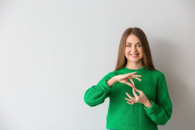 Işık arka planda işaret dilini kullanan genç sağır dilsiz kadın