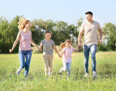 Mutlu aile yaz günü parkta koşuyor.
