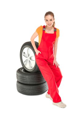 Beyaz arka planda araba lastikleri ile üniforma genç kadın tamirci