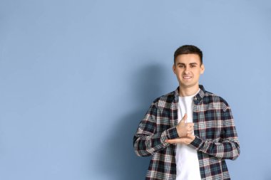 Gri arka planda işaret dilini kullanan genç sağır dilsiz adam