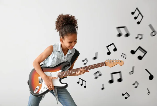 African-American girl playing guitar against light background — Stock Photo, Image