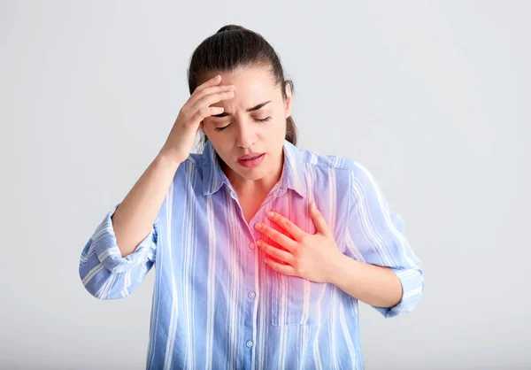 Junge Frau erleidet Herzinfarkt vor hellem Hintergrund — Stockfoto