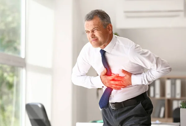 Зрілий чоловік страждає від серцевого нападу в офісі — стокове фото