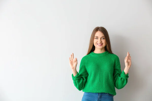 Young deaf mute woman using sign language on light background — Stock Photo, Image