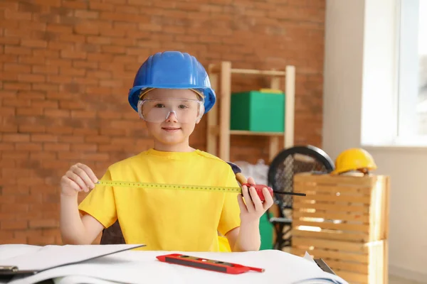 Cute little architect at table indoors — Stock Photo, Image