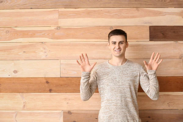 Young deaf mute man using sign language on wooden background — Stock Photo, Image