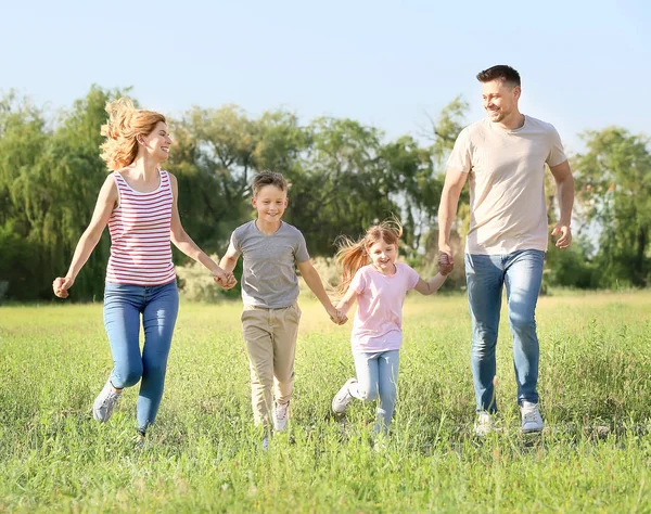 Lycklig familj som springer i parken på sommardagen — Stockfoto