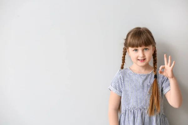 Cute deaf mute girl using sign language on light background — Stock Photo, Image