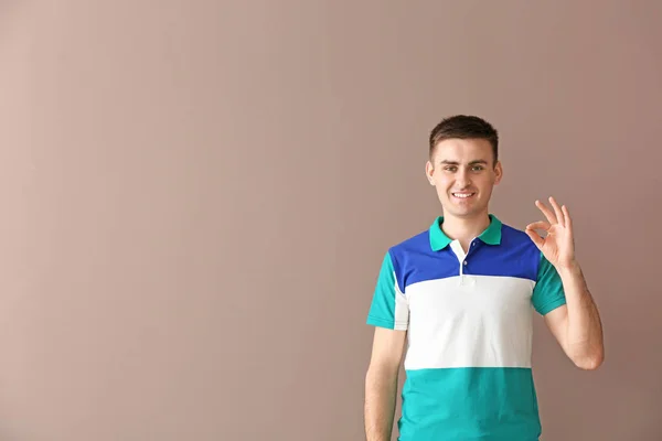 Young deaf mute man using sign language on color background — Stock Photo, Image