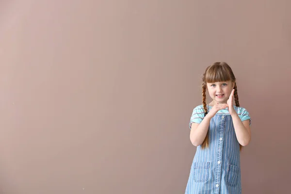 Carino sordomuto ragazza utilizzando il linguaggio dei segni su sfondo di colore — Foto Stock