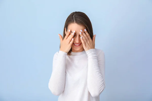 Beautiful young woman covering face with hands on light background — Stock Photo, Image