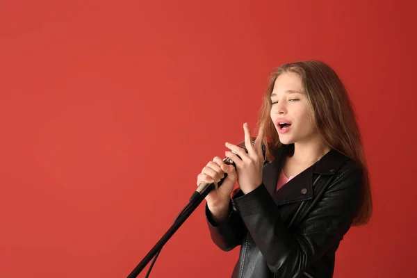Mladá dívka s mikrofonem zpívající proti barevnému pozadí — Stock fotografie