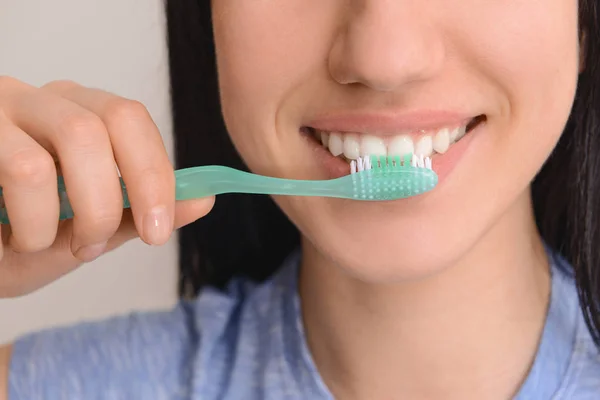 Frau mit Zahnbürste auf hellem Hintergrund, Nahaufnahme. Konzept der Zahnhygiene — Stockfoto