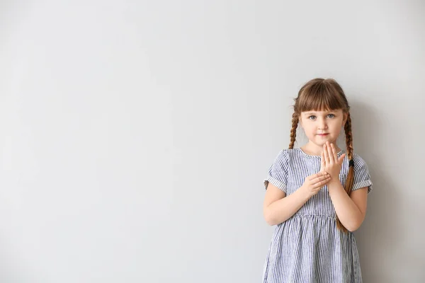 Carino sordomuto ragazza utilizzando il linguaggio dei segni su sfondo chiaro — Foto Stock