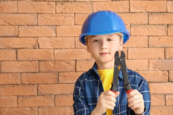 Cute little worker against brick wall — Stock Photo, Image