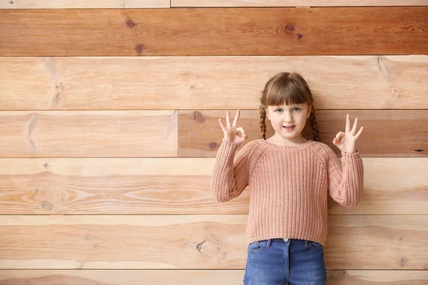 Roztomilá němá dívka používající jazyk na dřevěném pozadí — Stock fotografie