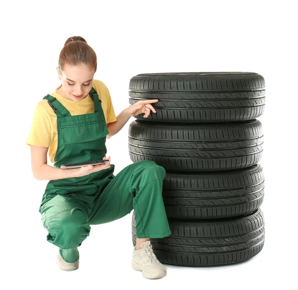 Jovem mecânica feminina em uniforme com computador tablet e pneus de carro no fundo branco — Fotografia de Stock