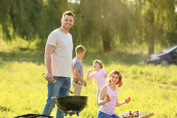 Man cooking tasty food on grill outdoors — Stock Photo, Image