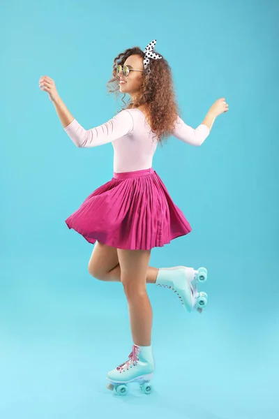 Hermosa mujer joven en patines sobre fondo de color — Foto de Stock