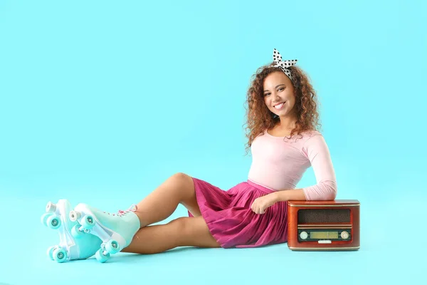 Hermosa mujer joven en patines y con receptor de radio retro contra fondo de color — Foto de Stock
