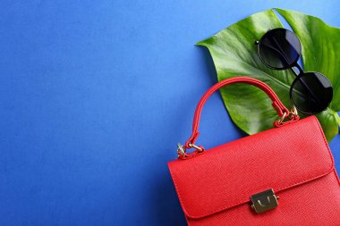 Renkli arka planda kadın çanta ile şık güneş gözlüğü