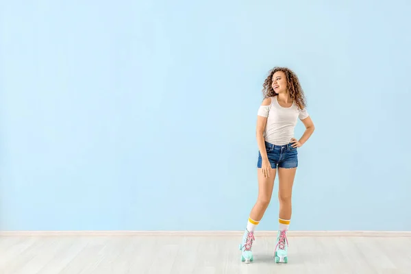 Beautiful young woman on roller skates against color wall — Stock Photo, Image