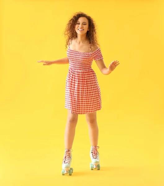 Beautiful young woman on roller skates against color background — Stock Photo, Image