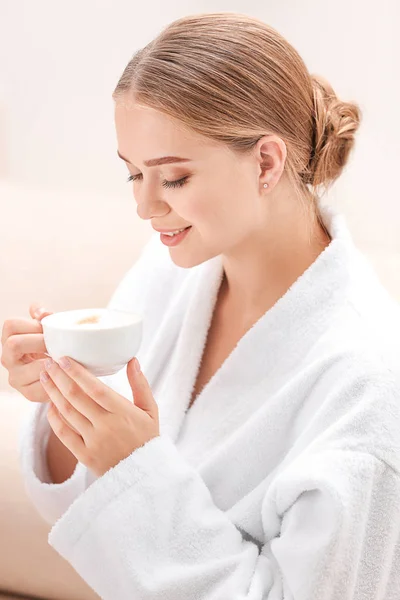 Mooie jonge vrouw drinken koffie in spa salon — Stockfoto