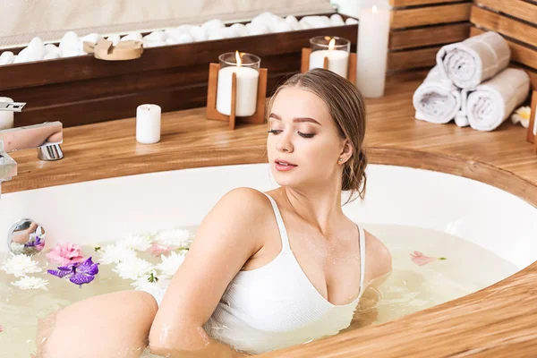 Beautiful young woman taking bath in spa salon — Stock Photo, Image