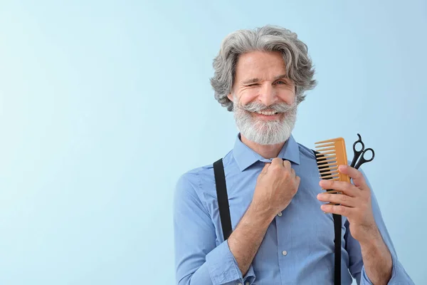 Mature male hairdresser on color background — Stock Photo, Image