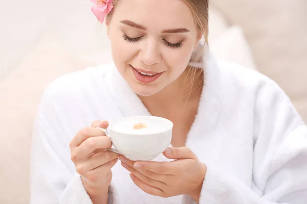 Beautiful young woman drinking coffee in spa salon — Stock Photo, Image