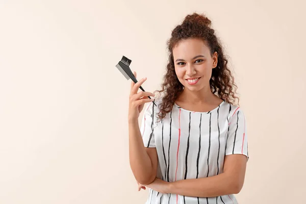 Beautiful African-American hairdresser on light background — Stock Photo, Image