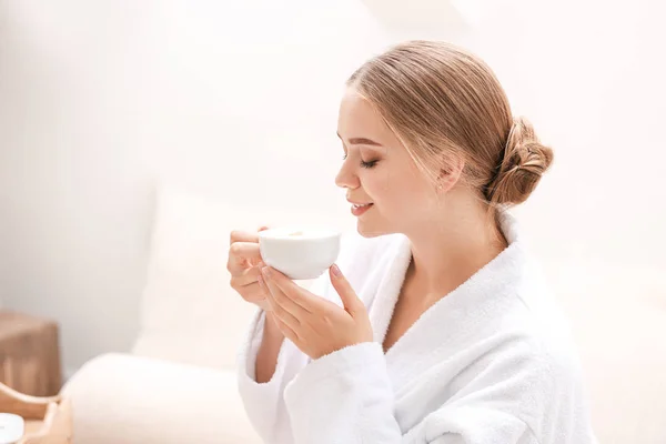 Beautiful young woman drinking coffee in spa salon — Stock Photo, Image