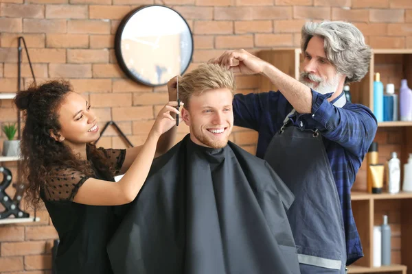 Coiffeurs professionnels travaillant avec le client dans un salon de beauté — Photo