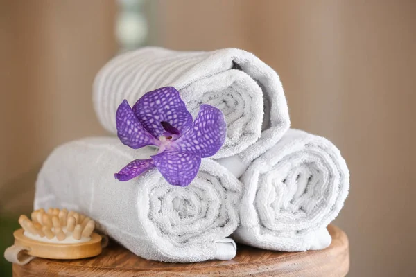 Rolled towels, flower and massage brush on table in spa salon