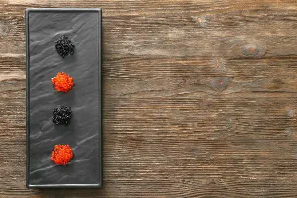 Placa con surtido de delicioso caviar sobre fondo de madera — Foto de Stock