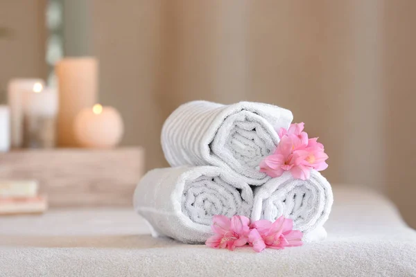 Toalhas enroladas na mesa de massagem no salão de spa — Fotografia de Stock