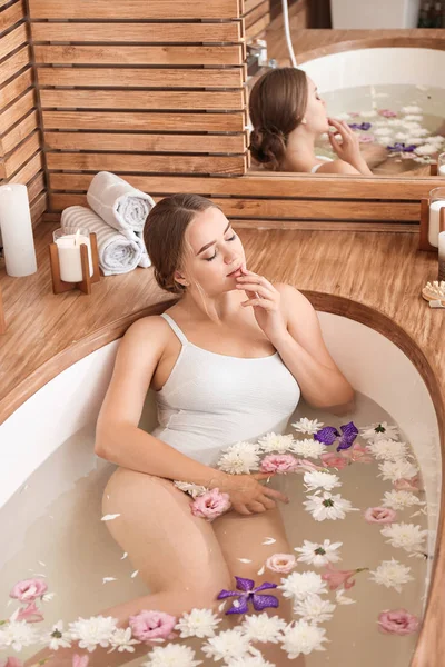 Mulher bonita tomando banho com flores no salão de spa — Fotografia de Stock