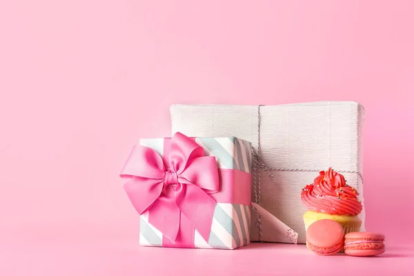 Beautiful gift boxes and sweets on color background