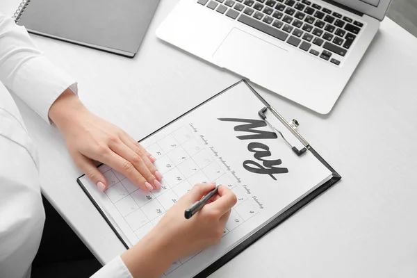 Jonge vrouw markerings datum in kalender aan tafel, close-up — Stockfoto